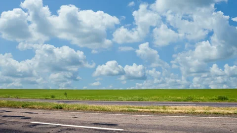 Asphalt road among green fields under cloudy sky Video stock 157300621