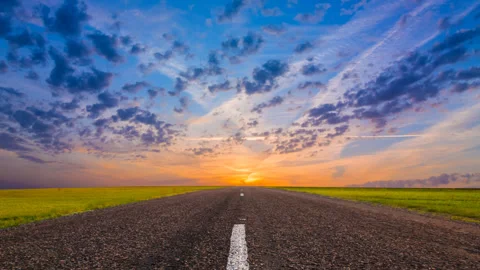 Asphalt road among green fields at the sunset 스톡 동영상 337651765