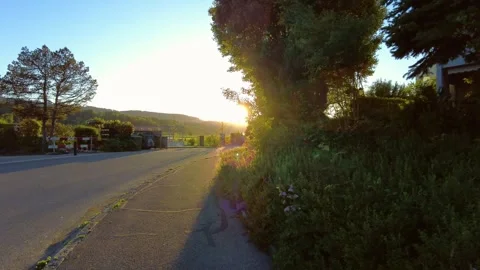 Asphalt road and sidewalk at sunset with bright sun lens flare Stock Footage 334870038