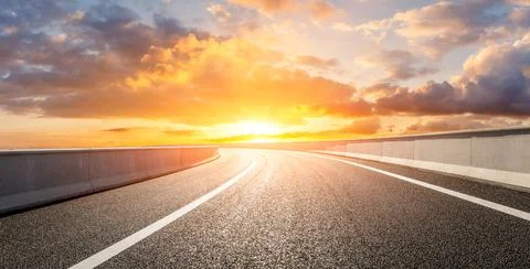 Asphalt road and sky clouds at sunset. Stock Photos