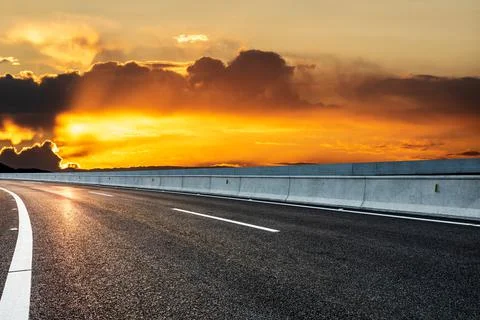Asphalt road and sky clouds at sunrise. Stock Photos