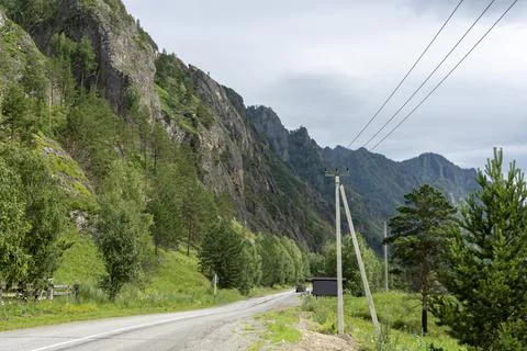 Asphalt road between mountain peaks. warm summer day Stock Photos