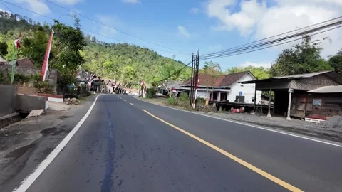 Asphalt road curves gently through village streets Vidéo 345154185