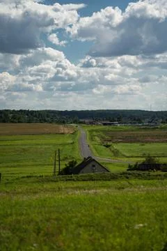 An asphalt road in the distance between fields. Thick clouds over the road Stock Photos