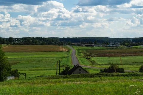 An asphalt road in the distance between fields. Thick clouds over the road Stock Photos
