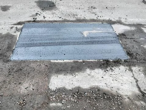 Asphalt road with a freshly sealed rectangular section of asphalt Stock Photos