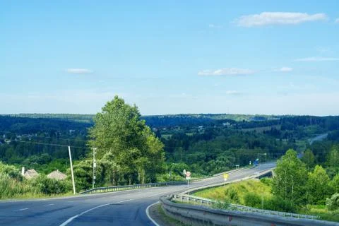 Asphalt road going through the forest on a summer sunny day Stock Photos