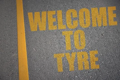 Asphalt road with text welcome to Tyre near yellow line. Stock Photos