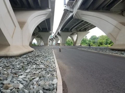 Asphalt road underneath a large bridge Stock Photos