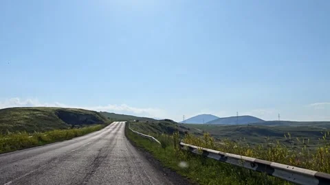 Asphalt road winds through hilly terrain with green grass on sides Stock Footage 339607168