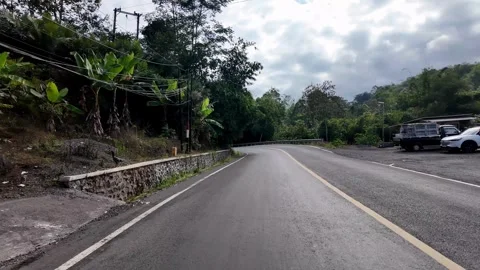 Asphalt road winds through lush green hills Видео 345153757