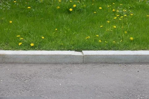 Asphalt section of pedestrian path with curbstone and grass, minimalism, ur.. Stock Photos
