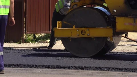 Asphalt working on the road. Compactor is driving over freshly poured asphalt Stock Footage 154411976