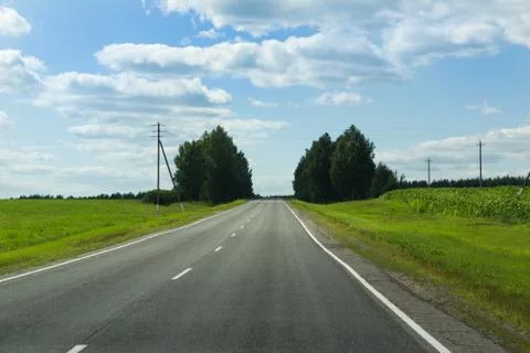 The asphalted way paved along fields Stock Photos