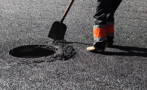 Asphalting in progress, worker with a shovel Stock Photos