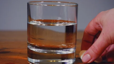 Aspirin or effervescent tablet, dissolves in a glass of water on the table close Stock Footage 103423163