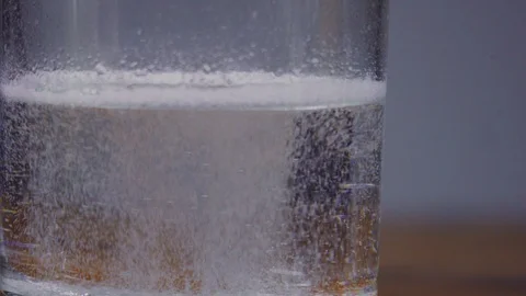 Aspirin or effervescent tablet, dissolves in a glass of water on the table close Stock Footage 103423220