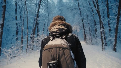 Aspiring photorapher backpacker walking in evening forest snowflakes falling 動画素材 123351878