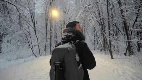 Aspiring photorapher backpacker walking in evening forest snowflakes falling Video stock 123484128