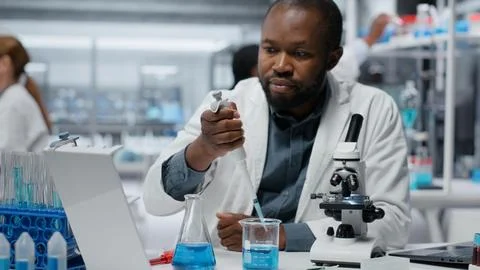 Assay development expert pipetting reactant into solution for purity analysis Stock Photos