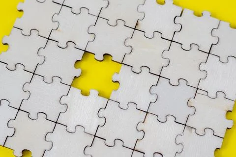 Assembled puzzle background. One missing wooden puzzle on a yellow background Stock Photos
