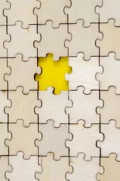 Assembled puzzle background. One missing wooden puzzle on a yellow background Stock Photos