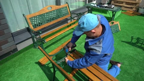 Assembler guy working with electric screwdriver making new outdoor furniture Stock Footage 145864928