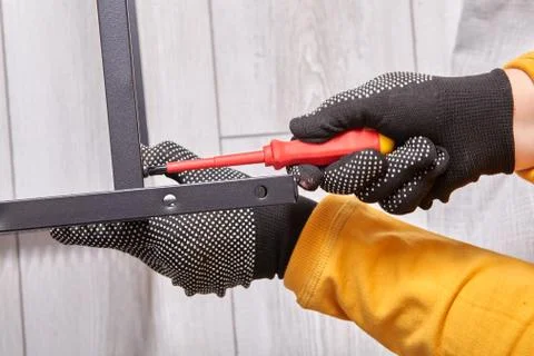 Assembler is mounting flat-pack shelf while tightening screws of it's metal Stock Photos