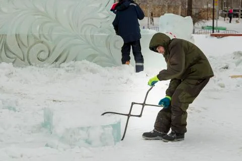 Assembler with steel tongs pulls ice block 写真素材