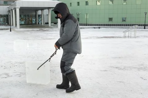 Assembler with steel tongs pulls ice block 스톡 사진