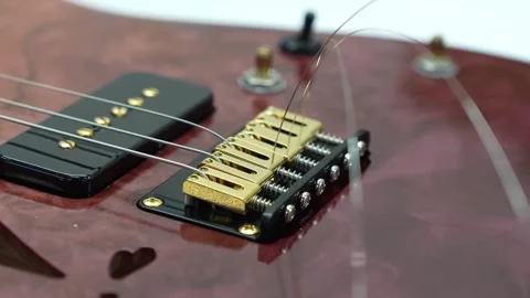 Assembling and securing guitar strings to a bridge Stock Footage 317138233
