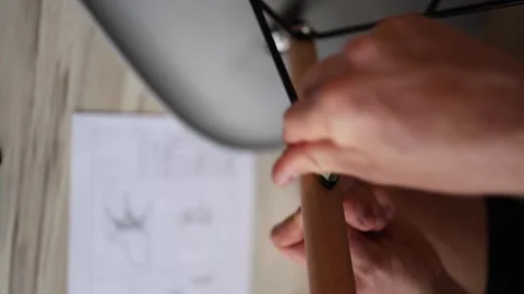 Assembling a chair at home with focused hands tightening bolts in clean composit Stock Footage 310009470