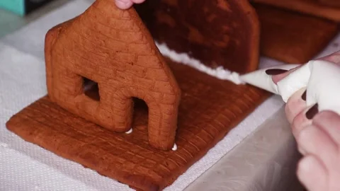 Assembling a Christmas Gingerbread House Connecting Roof Parts with Icing Stock Footage 345611239