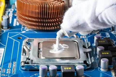 Assembling a computer in white gloves, applying thermal paste to the processo Foto stock