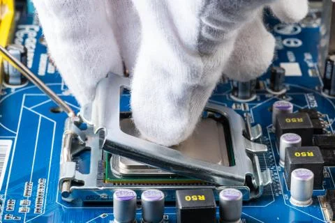 Assembling a computer in white gloves, installing a processor in its socket 写真素材