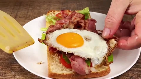 Assembling a delicious breakfast sandwich with bacon eggs and balsamic sauce Stock Footage 325032752