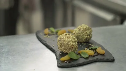 Assembling of dessert dish, chocolate mousse balls with crushed nuts Stockbeeldmateriaal 72437993