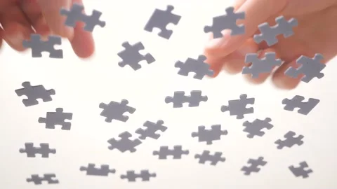 Assembling jigsaw puzzle. Pieces of a jigsaw puzzle interconnecting by male hand Video stock 132988022