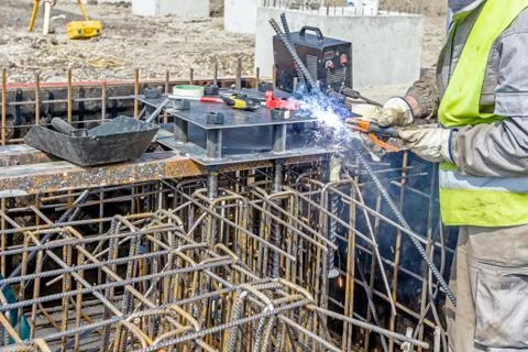 Assembling metal skeleton, welder is welding tied reinforcing rod and anchor Stock Photos