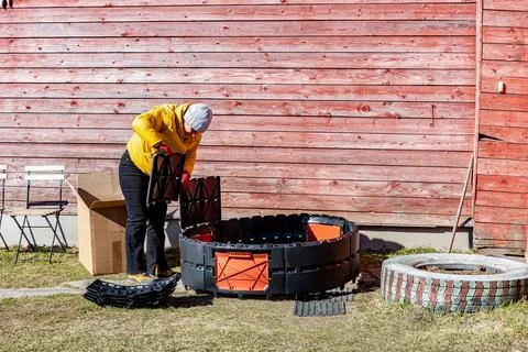 Assembling modular composter from plastic panels female gardener inserts se.. Stock Photos