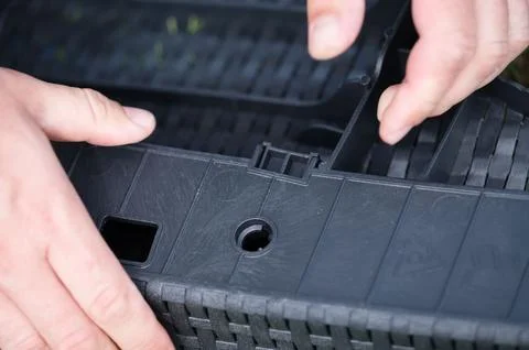 Assembling a modular plastic planter. Hands carefully connect the pieces. Stock Photos