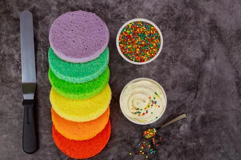 Assembling rainbow layer cake with white cream. Stock Photos
