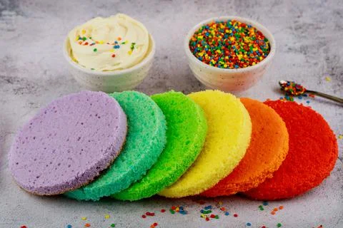 Assembling rainbow layer cake with white cream. Stock Photos