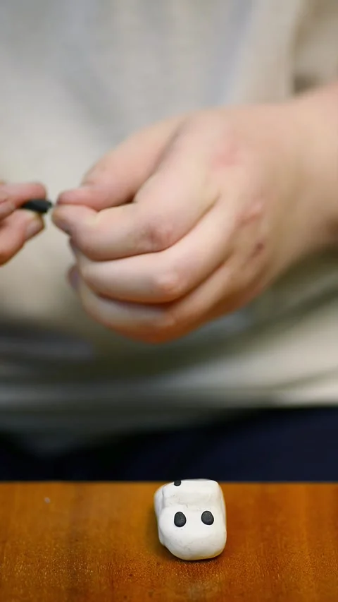 Assembling tiny decorative components onto a clay figurine base close up Stock Footage 342907574