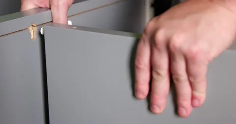 Assembling two pieces of grey wooden furniture together at home by male hands Stock Footage 150154294