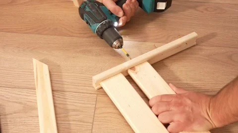 Assembling a wooden shelving structure using a screwdriver. A man uses screws to Vídeo Stock 342422984