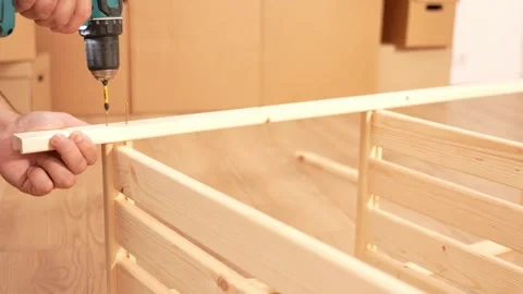 Assembling a wooden shelving structure using a screwdriver. A man uses screws to Vídeo Stock 342423027