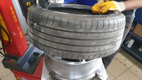 Assembly of auto tires, Mechanic in the workshop serviced the car wheels Video stock 120451318