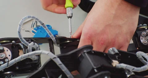 Assembly of a complex mechanism with a screwdriver.hands of a working man close Stock Footage 163243092