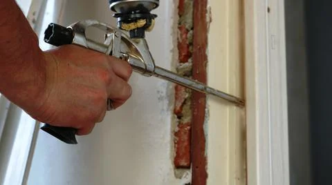 An assembly device in a man's hand during foaming of a gap Stock Photos